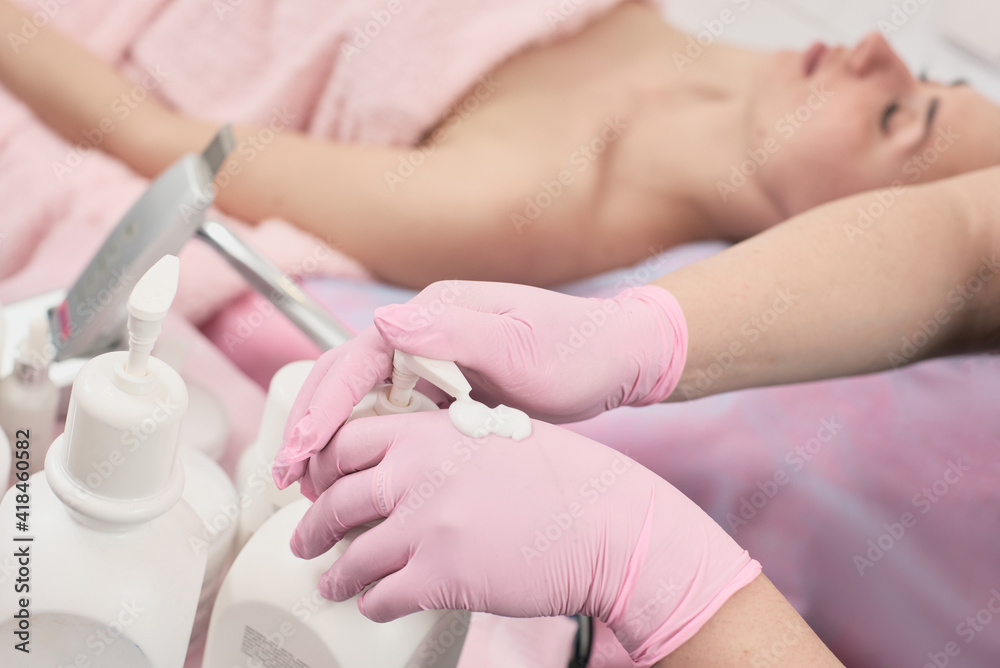 Fototapeta premium Closeup photo of professional beautician in medical gloves applying antiseptic cream on hands before procedure