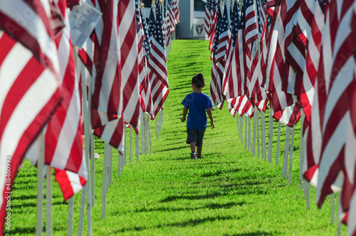 Boy walking between a row of American flags at public park