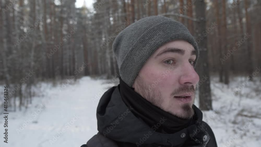 The video blogger walks and speaks to the camera against the background of a winter forest. A bearded man in a hat. The video blogger walks and speaks to the camera against the background of a winter forest. A bearded man in a hat.