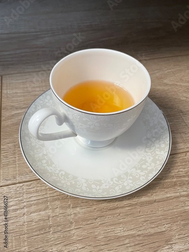 yellow tea in a white cup on a saucer. aristocrats