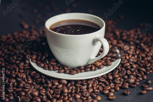 coffee beans sprinkled on a gray table and a cup saucer arabica drink