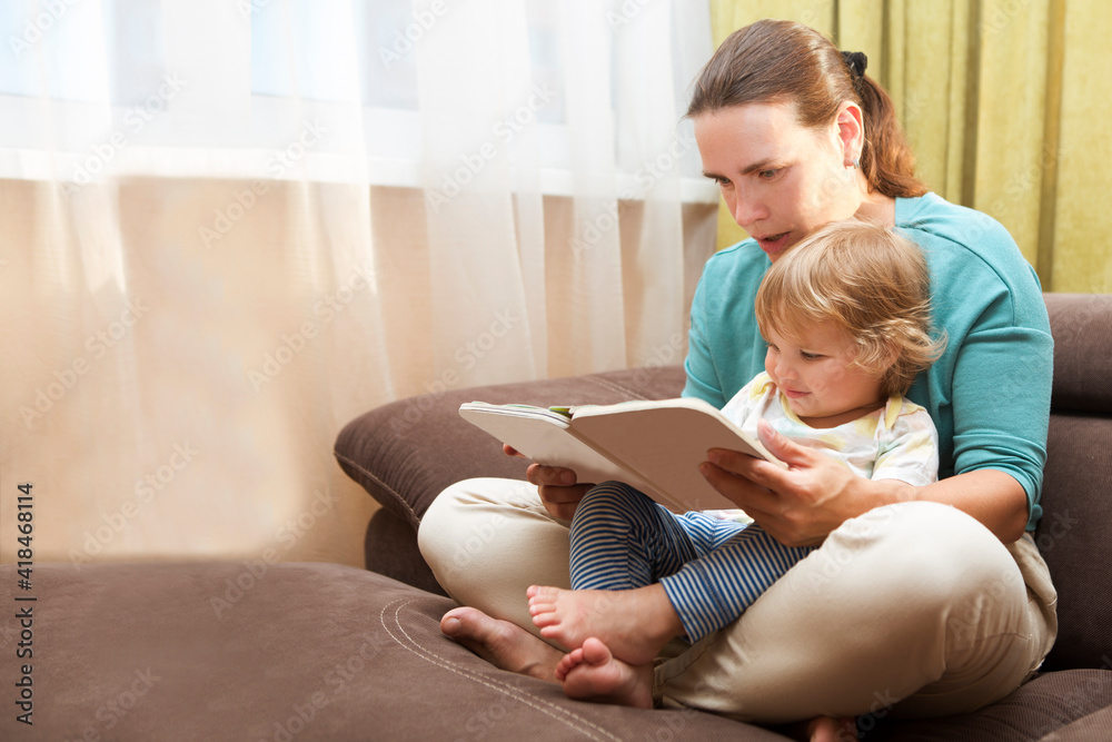 Mom and child reading a book free time weekend together at home