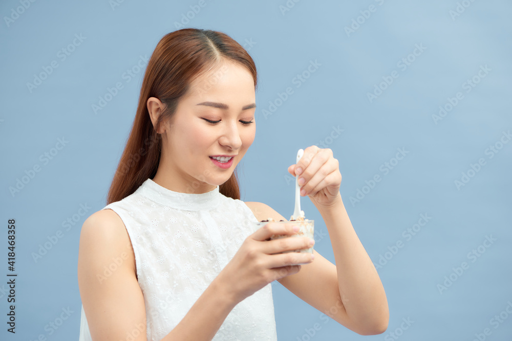 Attractive young woman enjoying a healthy meal eating a mixture of yoghurt and muesli with fruit Attractive young woman enjoying a healthy meal eating a mixture of yoghurt and muesli with fruit