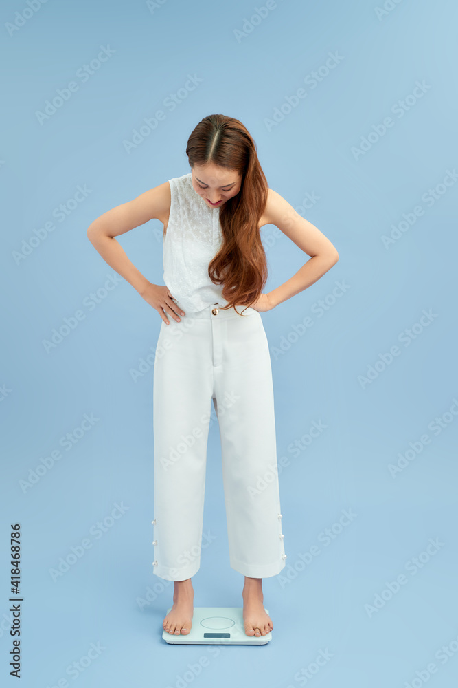 Shocked overweight woman standing on scales at home Shocked overweight woman standing on scales at home