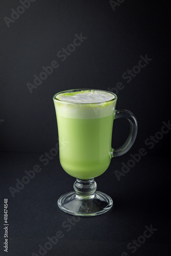 Matcha latte in a glass cup on black background.