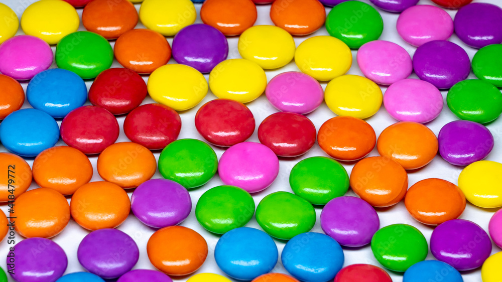 Selective focus of an array of colorful chocolate buttons on a white background. Selective focus of an array of colorful chocolate buttons on a white background.