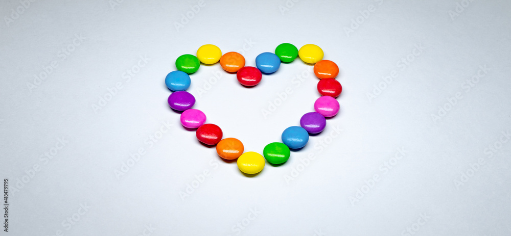 Selective focus of colorful button chocolates arranged in the shape of a heart.