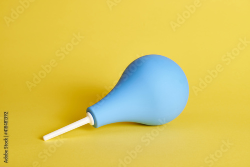 Konstfotografi A blue medical rubber constipation enema on yellow background with copy space