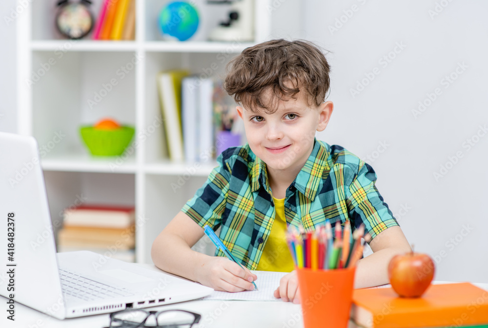 Smiling boy uses laptop at home. Distance learning concept Smiling boy uses laptop at home. Distance learning concept