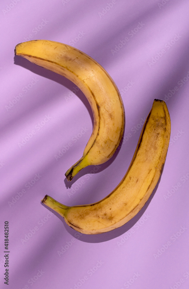 Bananas on purple background with fancy shadows, flat lay style minimal Bananas on purple background with fancy shadows, flat lay style minimal