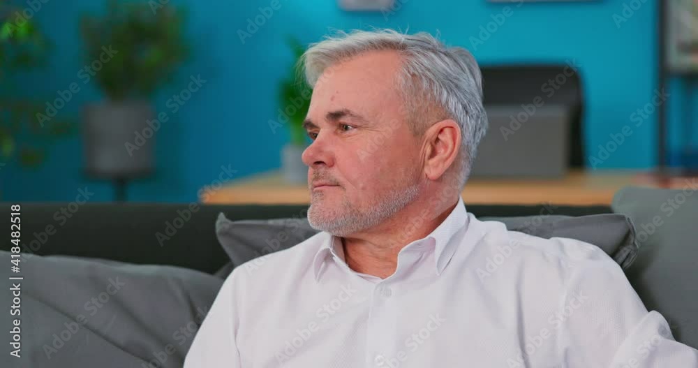 Portrait of gloomy mature 60s gray haired man posing at home or retirement house. Old pensive grandfather feeling loneliness with painful face expression. Portrait of gloomy mature 60s gray haired man posing at home or retirement house. Old pensive grandfather feeling loneliness with painful face expression.