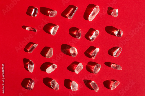 Samples of natural mineral from geological collection - rolled colorless Rock crystal gem stone on red background