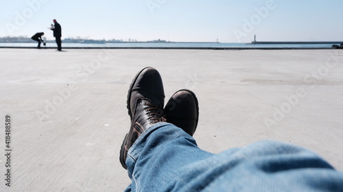 Turkey. Istanbul 04.03.2021. Istanbul bosphorus and a man foot wearing winter and brown boots and extends to sea of marmara and people taking photo through haydarpasa main train station and lighthouse photo