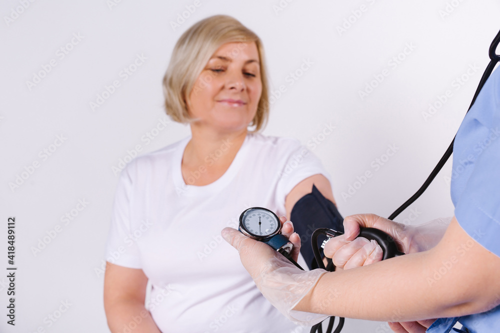 Cropped photo. A nurse measures the blood pressure of an older woman. White background with empty space. Cropped photo. A nurse measures the blood pressure of an older woman. White background with empty space.