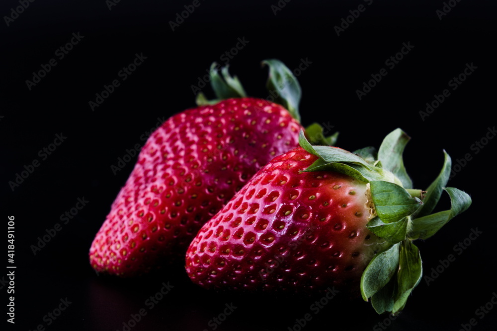 Two strawberries isolated on black background, close up Two strawberries isolated on black background, close up