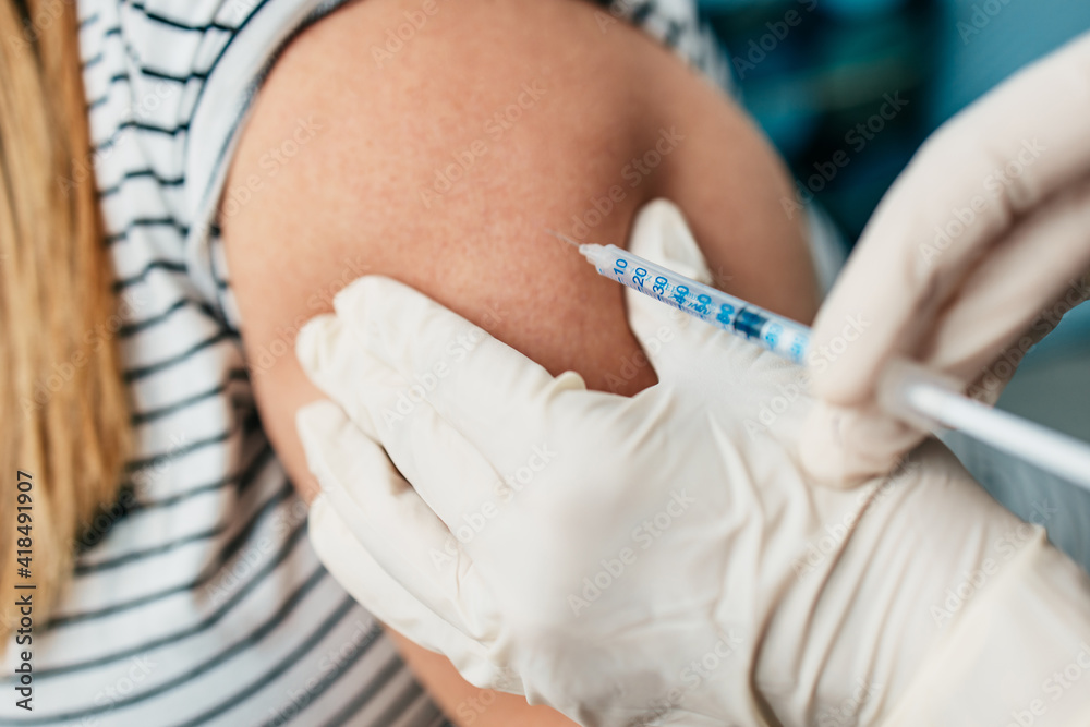 Female doctor vaccinating middle age female patient at home. Coronavirus or Covid-19 home vaccination, prevention and pandemic protection concept. Female doctor vaccinating middle age female patient at home. Coronavirus or Covid-19 home vaccination, prevention and pandemic protection concept.