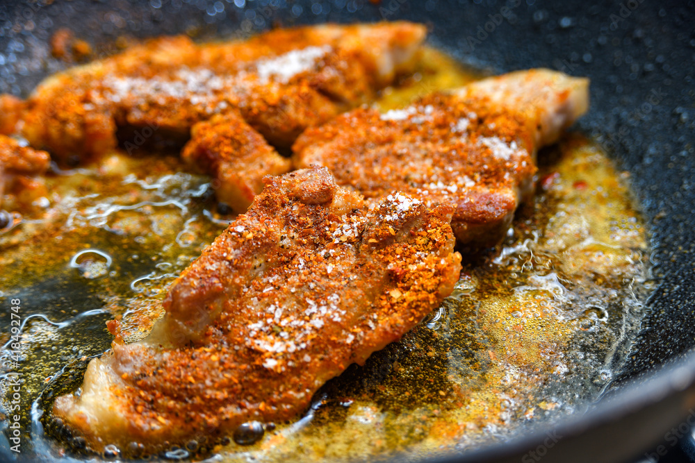Large pieces of meat with spices are fried in a pan, close-up photo. Large pieces of meat with spices are fried in a pan, close-up photo.