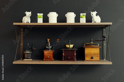 Antique vintage coffee grinder on wooden wall shelf and black background