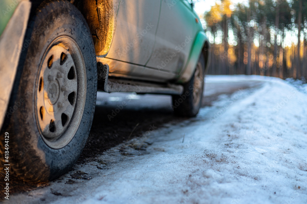  Closeup of car tires in winter on the dirt road covered with ice, snow and gravel