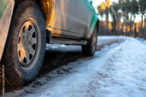  Closeup of car tires in winter on the dirt road covered with ice, snow and gravel