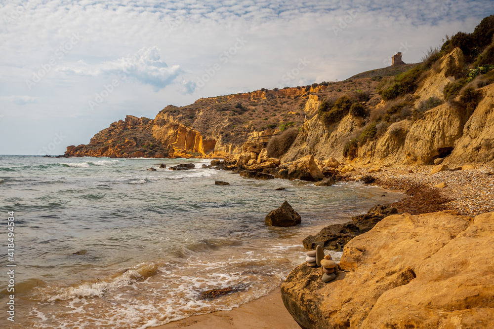 View of the Le Pergole beach in Sicily. The colorful rocks contrast beautifully with the color of the sea. A warm summer afternoon.
