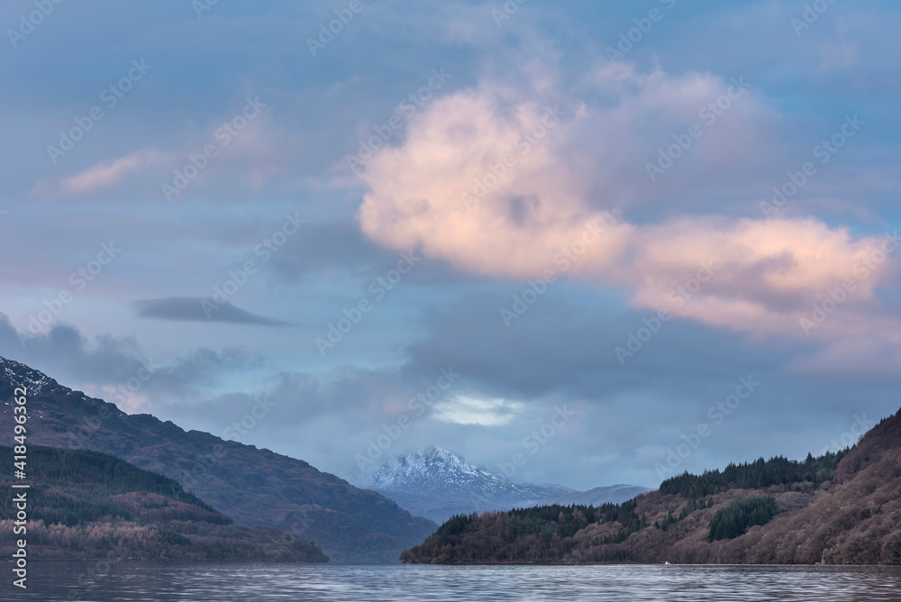 Majestic landscape image across Loch Lomond looking towards snow capped Ben Lui mountain peak in Scottish Highlands