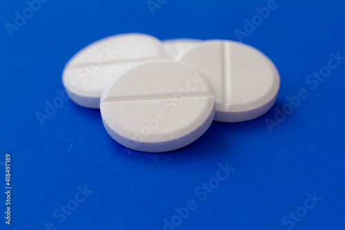 White round medical pills on a colourful background. Scattered white pills on the table. The concept of medicine, pharmacy and healthcare. Space for text or logo.