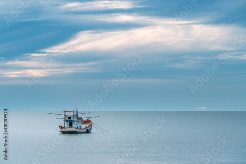 One wooden fishing boat moored on the sea in the morning  the expanse of water  beautiful morning sky  feeling of peace. A fishing boat of local fishermen in Thailand.