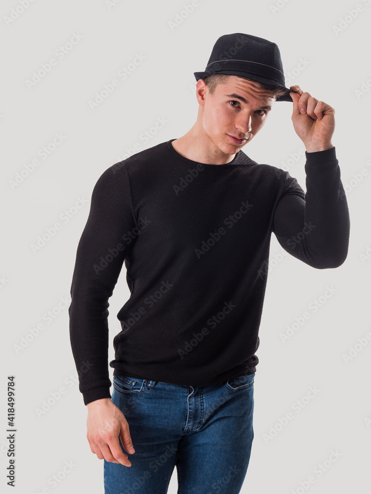 Young man tipping his hat, touching fedora hat on his head, in studio shot on white background Young man tipping his hat, touching fedora hat on his head, in studio shot on white background