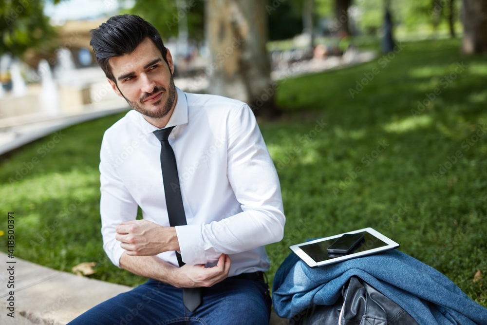 Obraz premium Portrait of young businessman sitting outdoors in park, resting.
