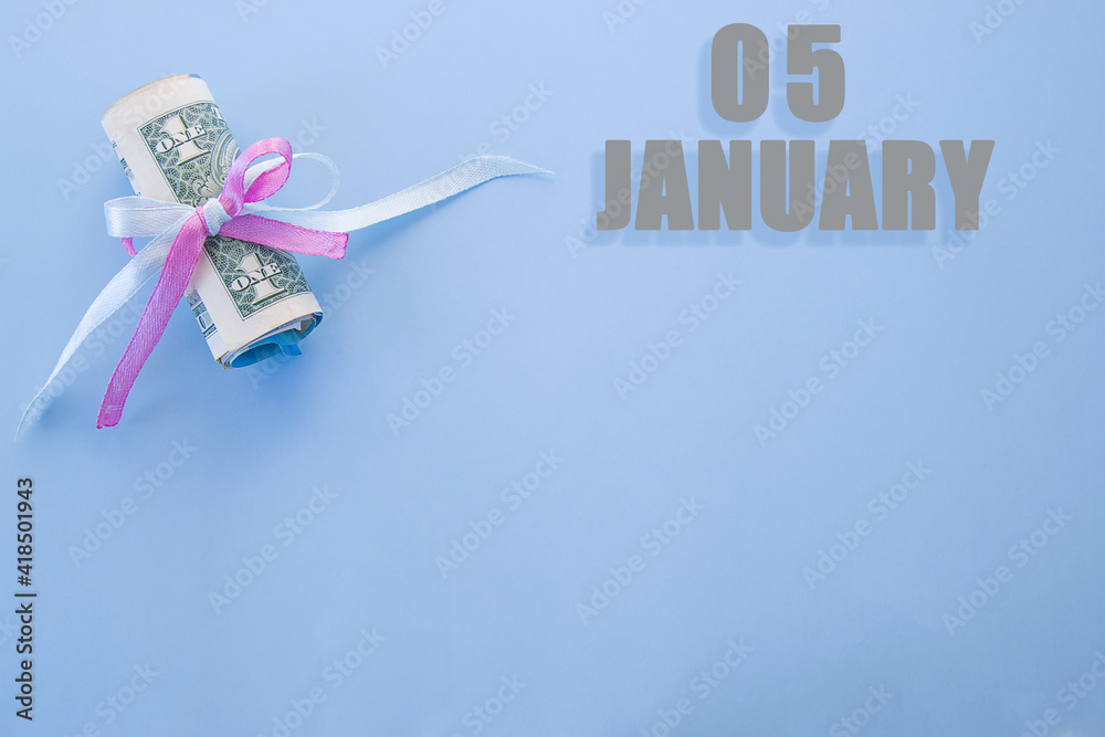 calendar date on blue background with rolled up dollar bills pinned by blue and pink ribbon with copy space. January 5 is the fifth day of the month