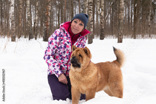 A Happy woman with dog chow chow in winter outdoors