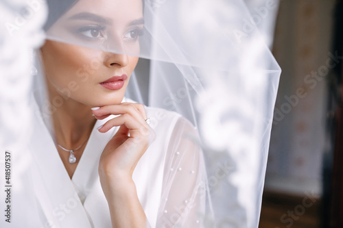Foto charming bride wrapped in a veil. Wedding morning.