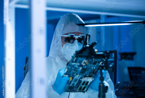 Microelectronics engineer works in a modern scientific laboratory on computing systems and microprocessors. Electronic factory worker is testing the motherboard and coding the firmware.