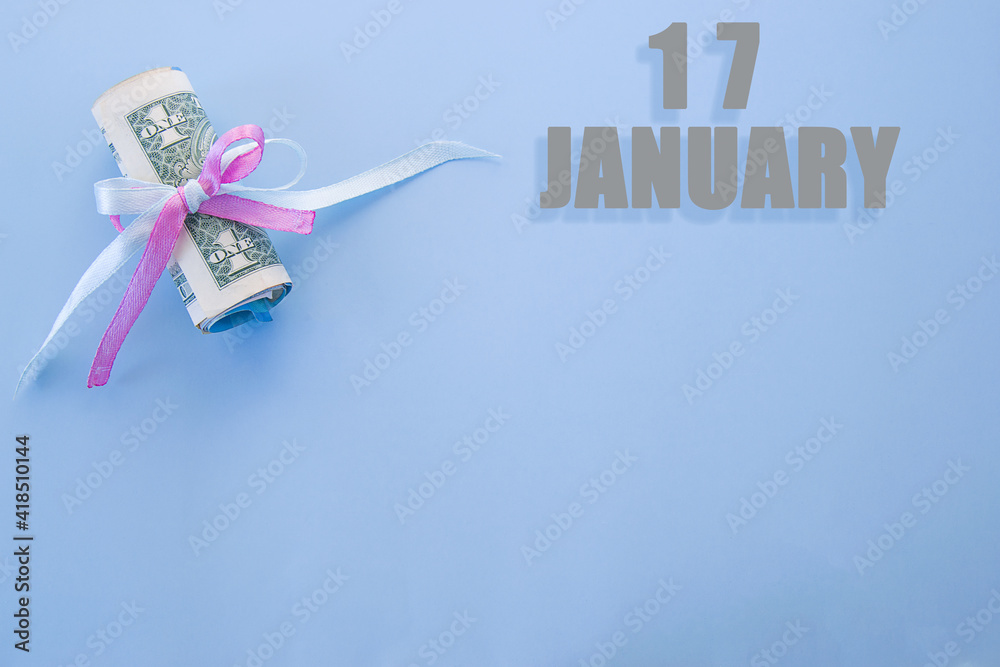 calendar date on blue background with rolled up dollar bills pinned by blue and pink ribbon with copy space. January 17 is the seventeenth day of the month