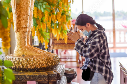 Obraz na plátne Beautiful girl paying respect to buddha statue