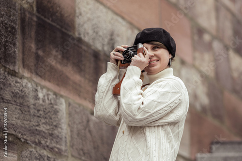 woman photographer in birette with an old camera in her hands takes pictures with smile