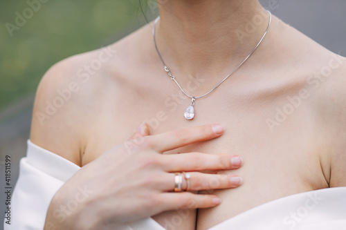The girl gently touches the necklace around her neck. Wedding morning of the bride. Advertising decorations. The woman goes on a date.