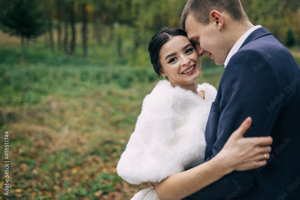 Cheerful bride and groom hug and smile in the autumn park during a walk. Cheerful bride and groom hug and smile in the autumn park during a walk.