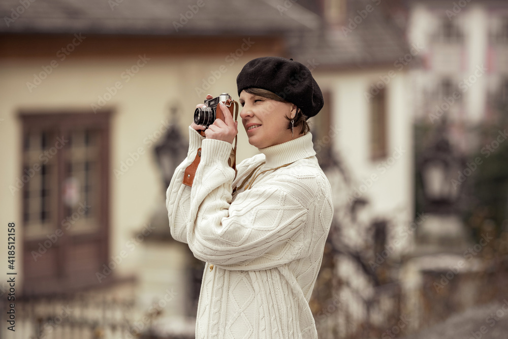 Fototapeta premium woman photographer in birette with an old camera in her hands takes pictures with smile