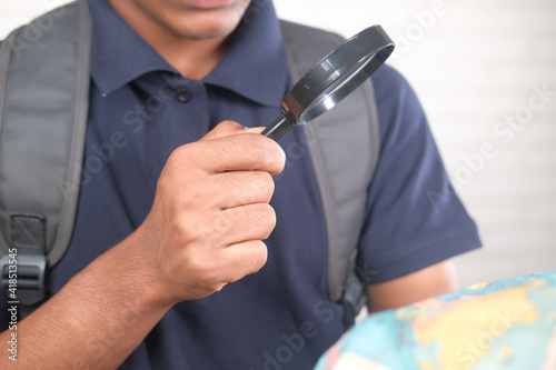 young man using magnifying glass looking something on map 