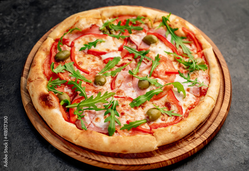 pizza with ham, tomatoes, cheese on a stone background