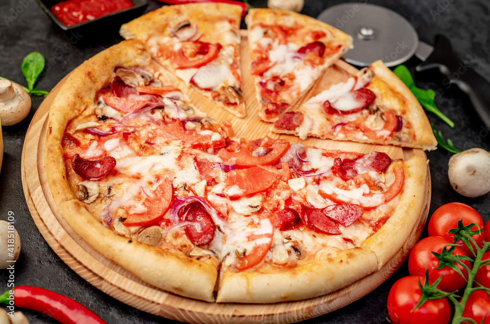 pizza with sausages, mushrooms, tomatoes and cheese on a stone background