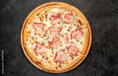 pizza with bacon, mushrooms and cheese on a stone background