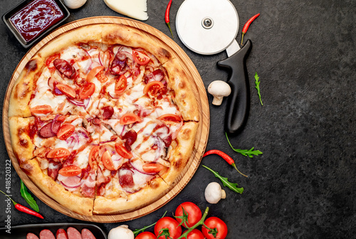 pizza with sausages, mushrooms, tomatoes and cheese on a stone background  with copy space for your text

