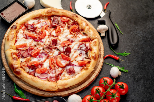 pizza with sausages, mushrooms, tomatoes and cheese on a stone background with copy space for your text

