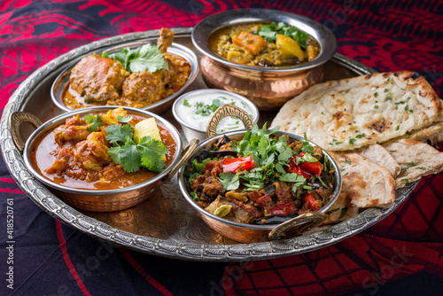 Traditional Indian curry dishes served with rice and pita bread as close-up on a traditional thali