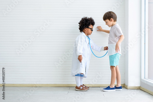 The child wears a doctor's suit and uses a stethoscope to examine the prostate gland.. © SizeSquare's