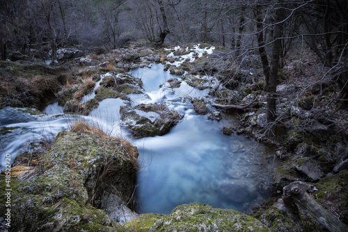 Waterfall in an ominous forest surrounded by leafless tree branches photo