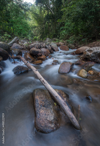 Waterfall landscape. Beautiful hidden waterfall in tropical rainforest. Foreground with big stones. Slow shutter speed, motion photography. Travel and adventure.